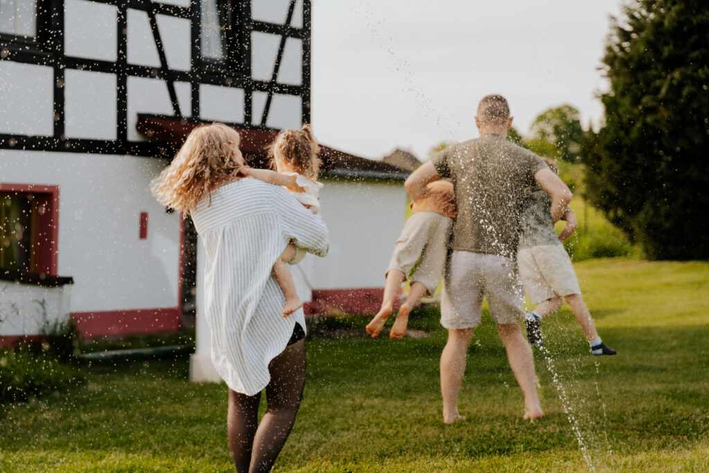 Eine Familie tanzt und dreht sich unter dem Wasser des Wasserschlauchs.